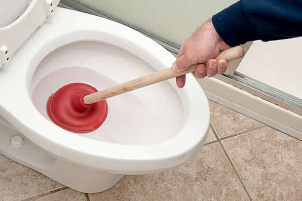 mano che cerca di sistemare uno scarico wc otturato